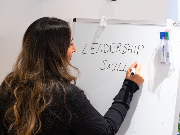 Image of a staff member writing 'Leadership Skills' on a whiteboard. 